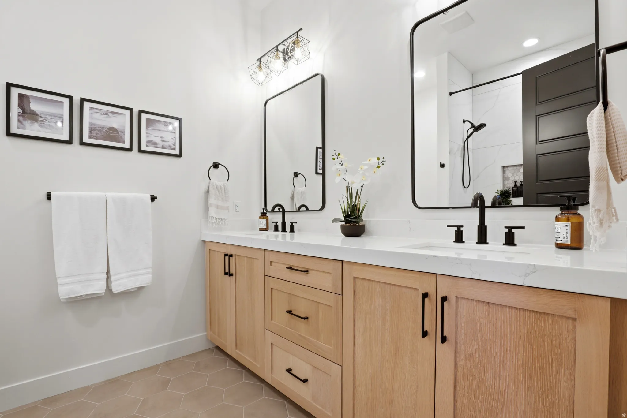 Dual vanity featuring light wood-finish cabinetry, white countertops, and matte black fixtures