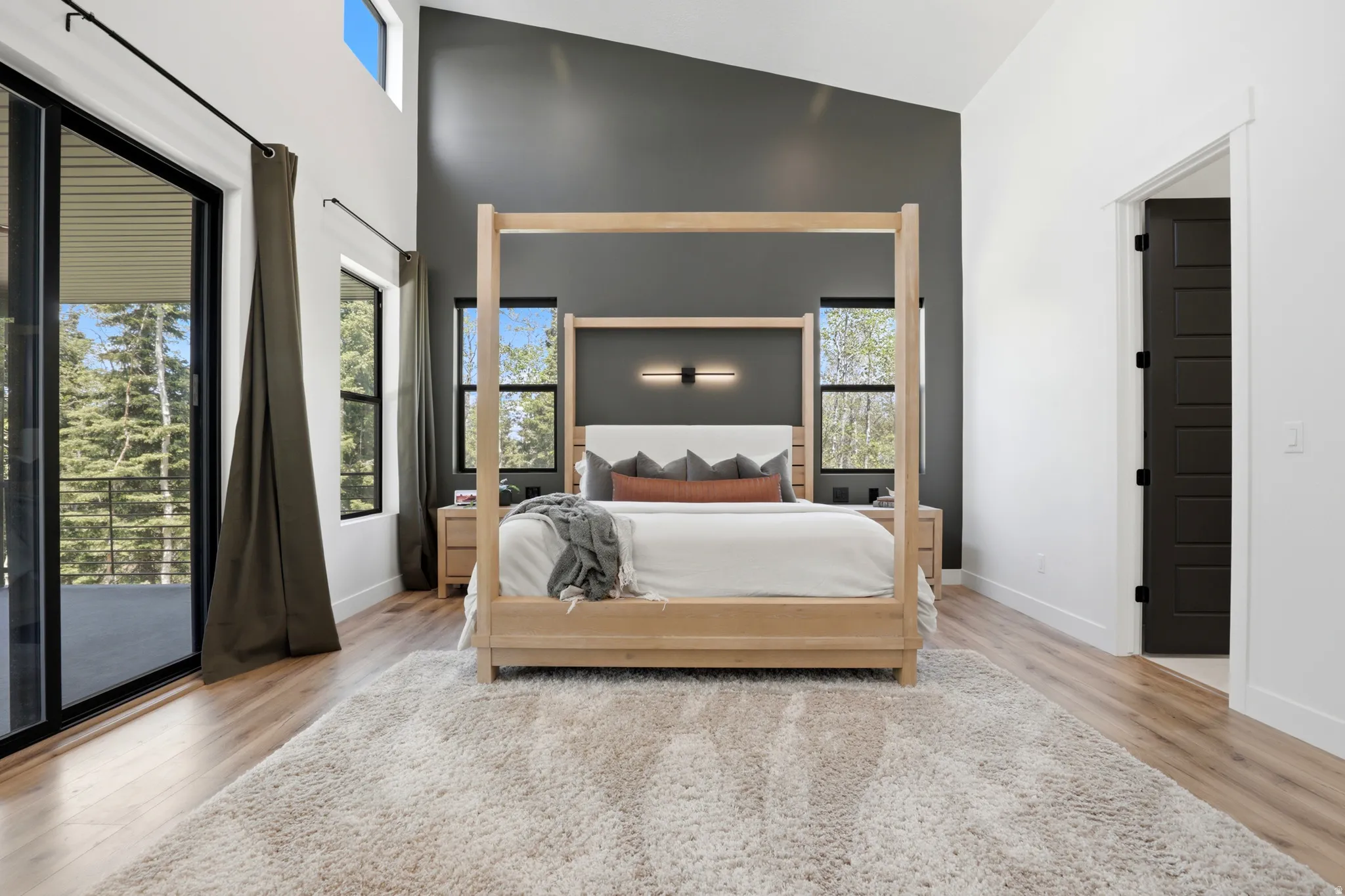 Vaulted ceiling bedroom with a dark accent wall, and a sliding glass door to an exterior balcony