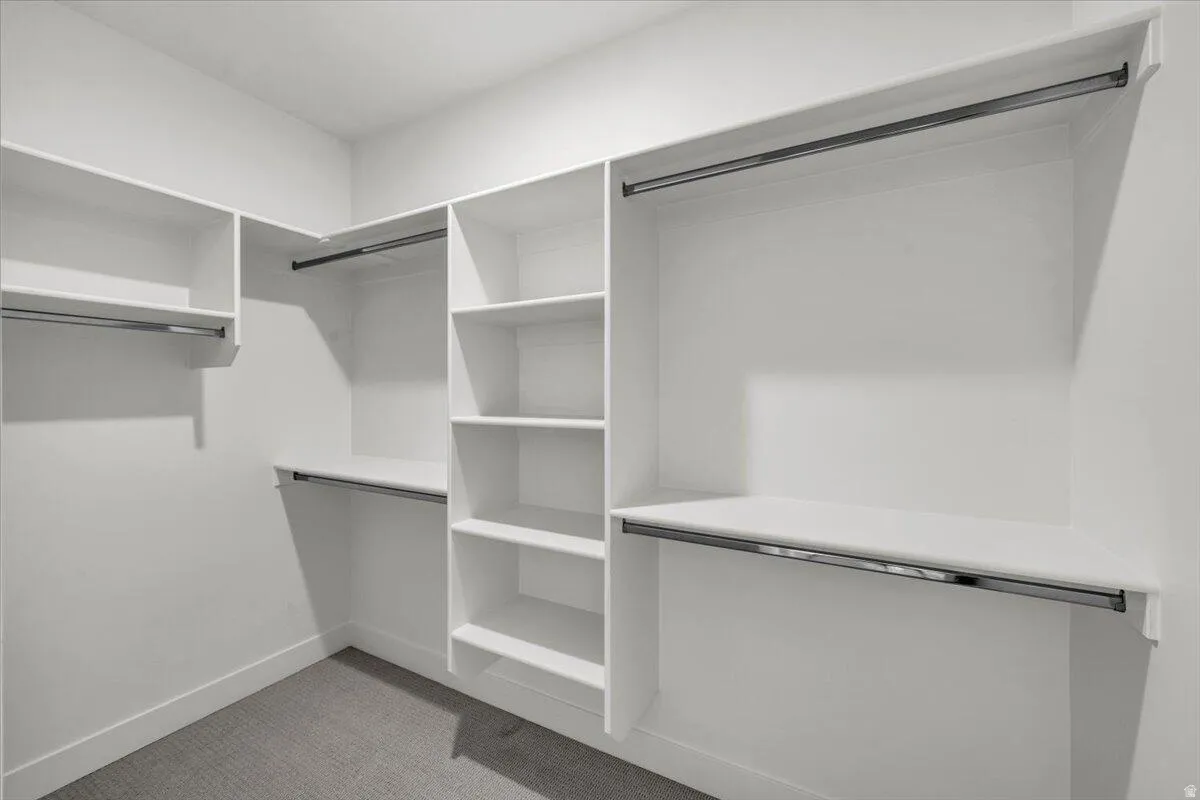 Walk in closet featuring light colored carpet