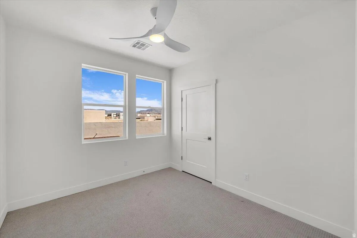 Carpeted spare room featuring baseboards and ceiling fan