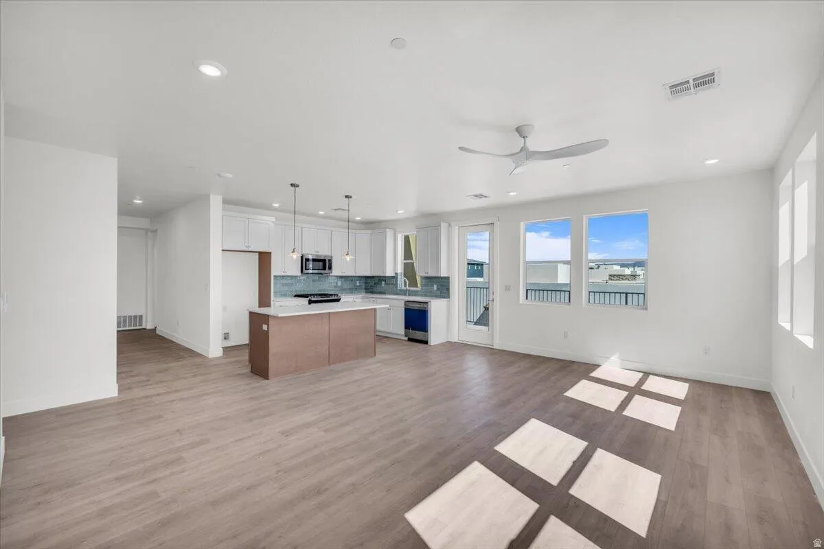 Kitchen featuring open floor plan, hanging light fixtures, a center island, light wood-type flooring, and two tone cabinets