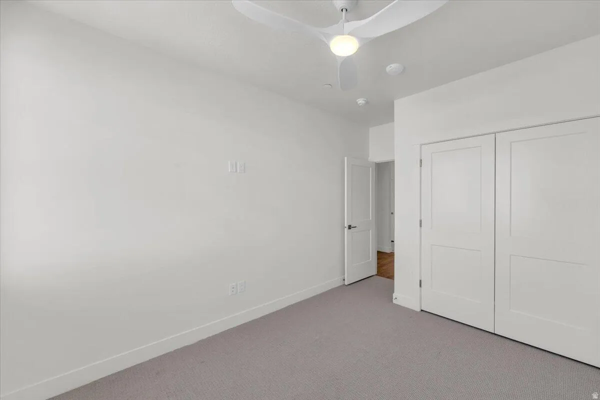 Unfurnished bedroom featuring carpet flooring, a closet, and a ceiling fan