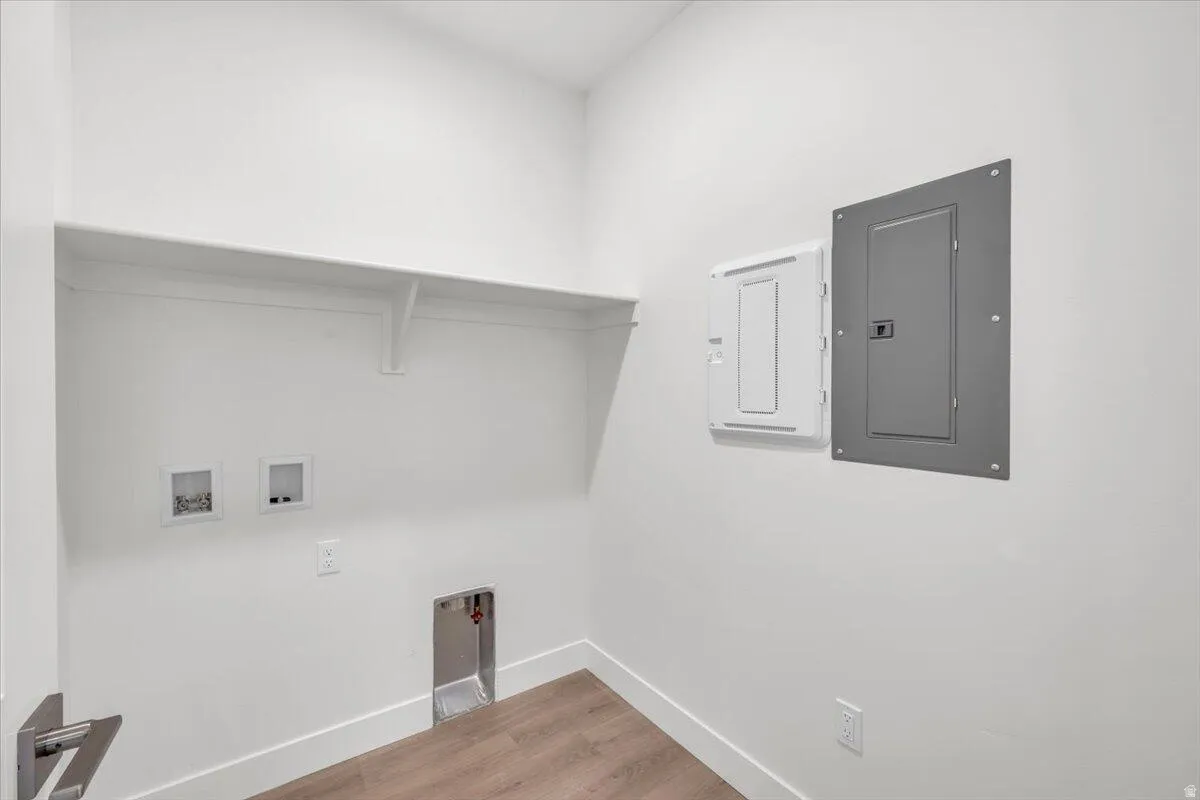 Laundry area featuring electric panel, hookup for a washing machine, and light wood-style flooring