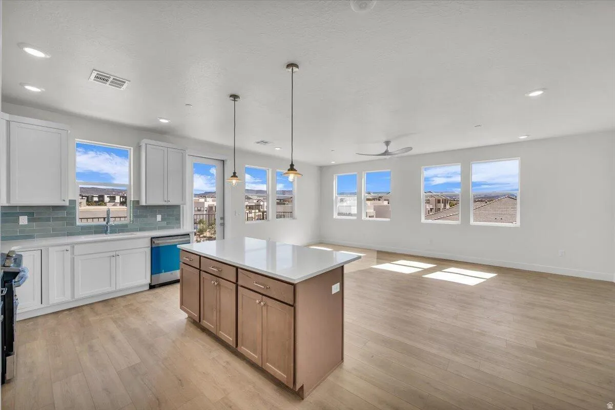 Dual tone kitchen featuring dual tone cabinetry, open floor plan, a kitchen island, hanging light fixtures, and light wood-style flooring
