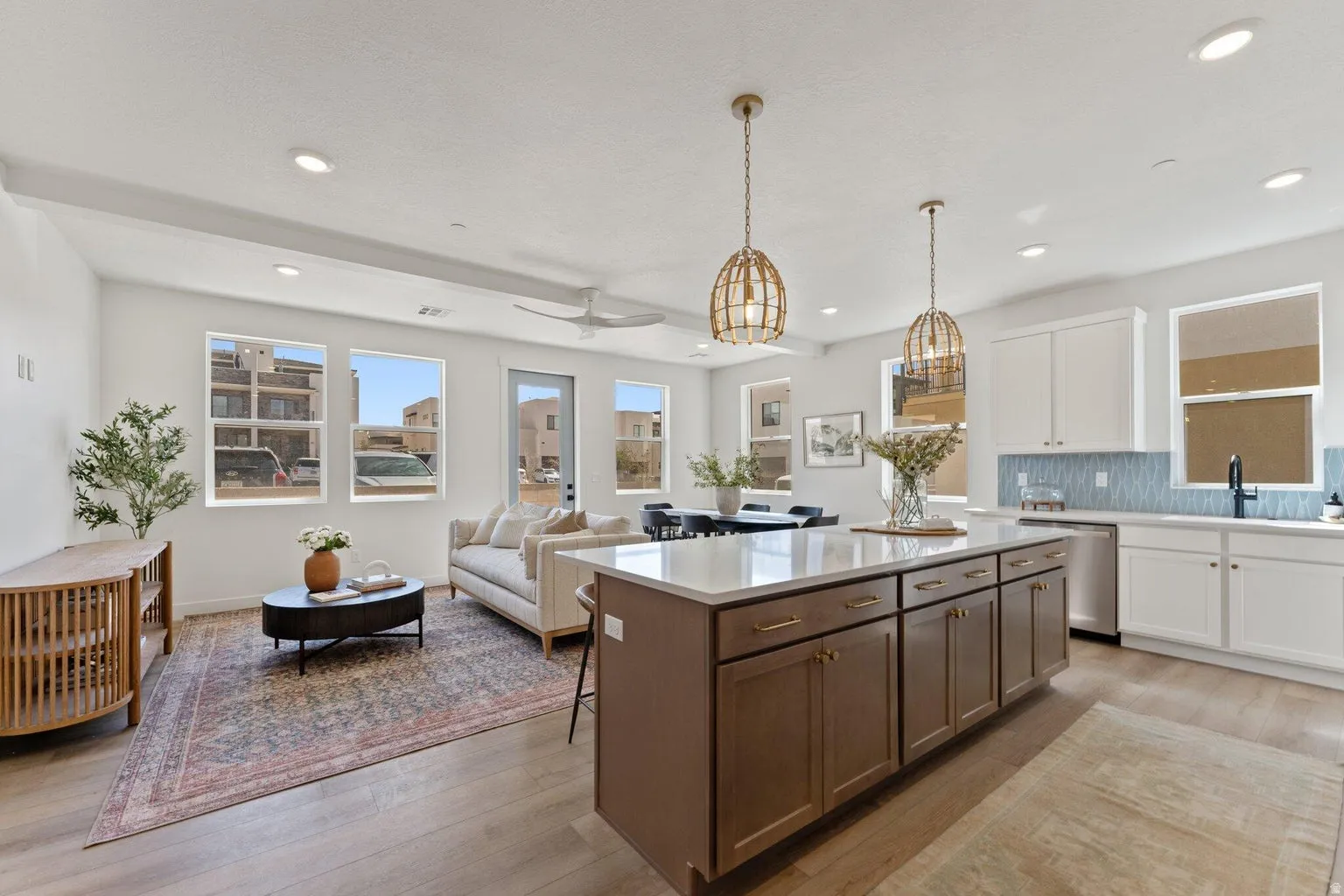 Kitchen with dual tone cabinetry, tasteful backsplash, a center island, light wood-type flooring, and decorative light fixtures