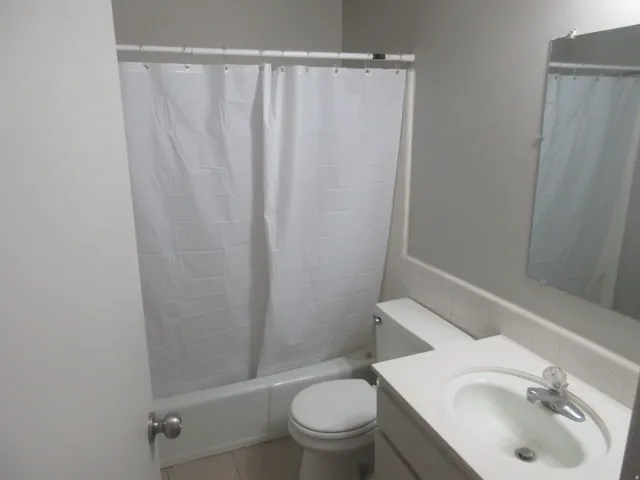 Full bathroom with vanity, shower / tub combo with curtain, and tile patterned floors