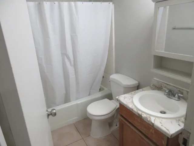 Full bath with vanity, shower / bath combo, and light tile patterned floors