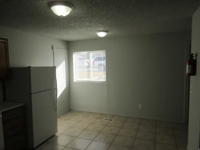 Unfurnished dining area featuring a textured ceiling and light tile patterned floors
