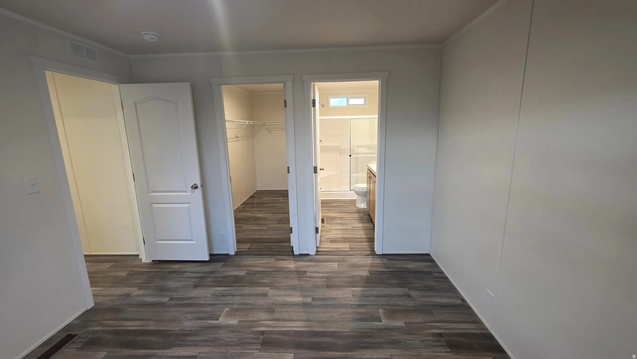 Unfurnished bedroom featuring dark wood-type flooring, a spacious closet, and connected bathroom