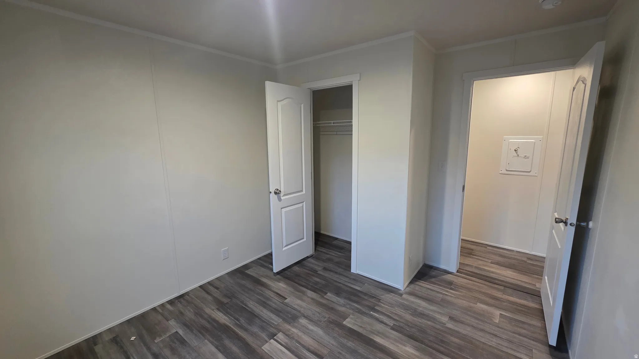 Unfurnished bedroom featuring dark wood-style flooring, a closet, and ornamental molding