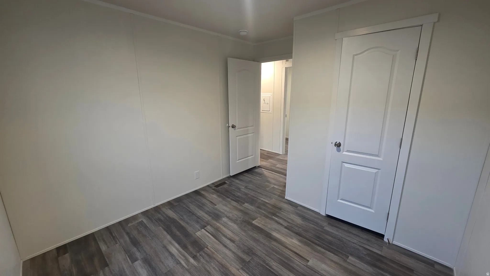 Unfurnished bedroom featuring dark wood-style floors and crown molding