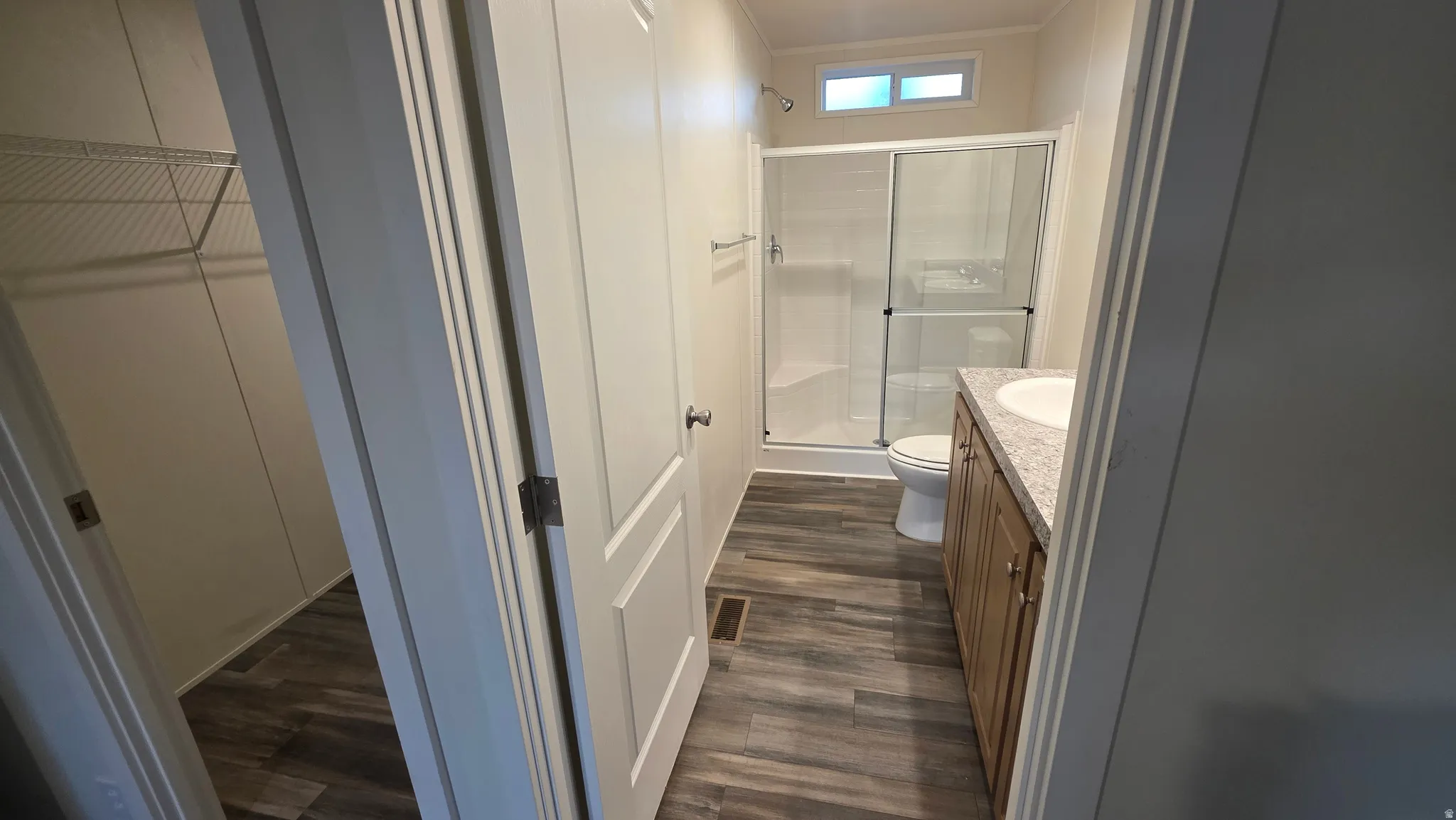 Full bathroom with a shower stall, a spacious closet, vanity, and dark wood-style flooring