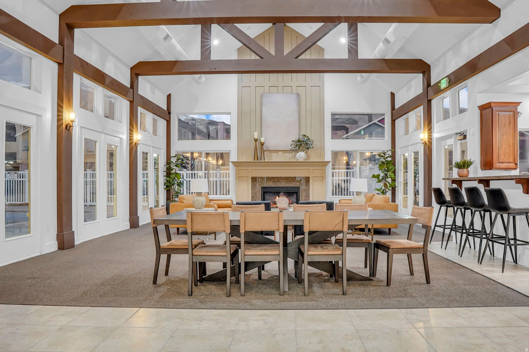 Dining area with vaulted ceiling, a lit fireplace, plenty of natural light, and light carpet