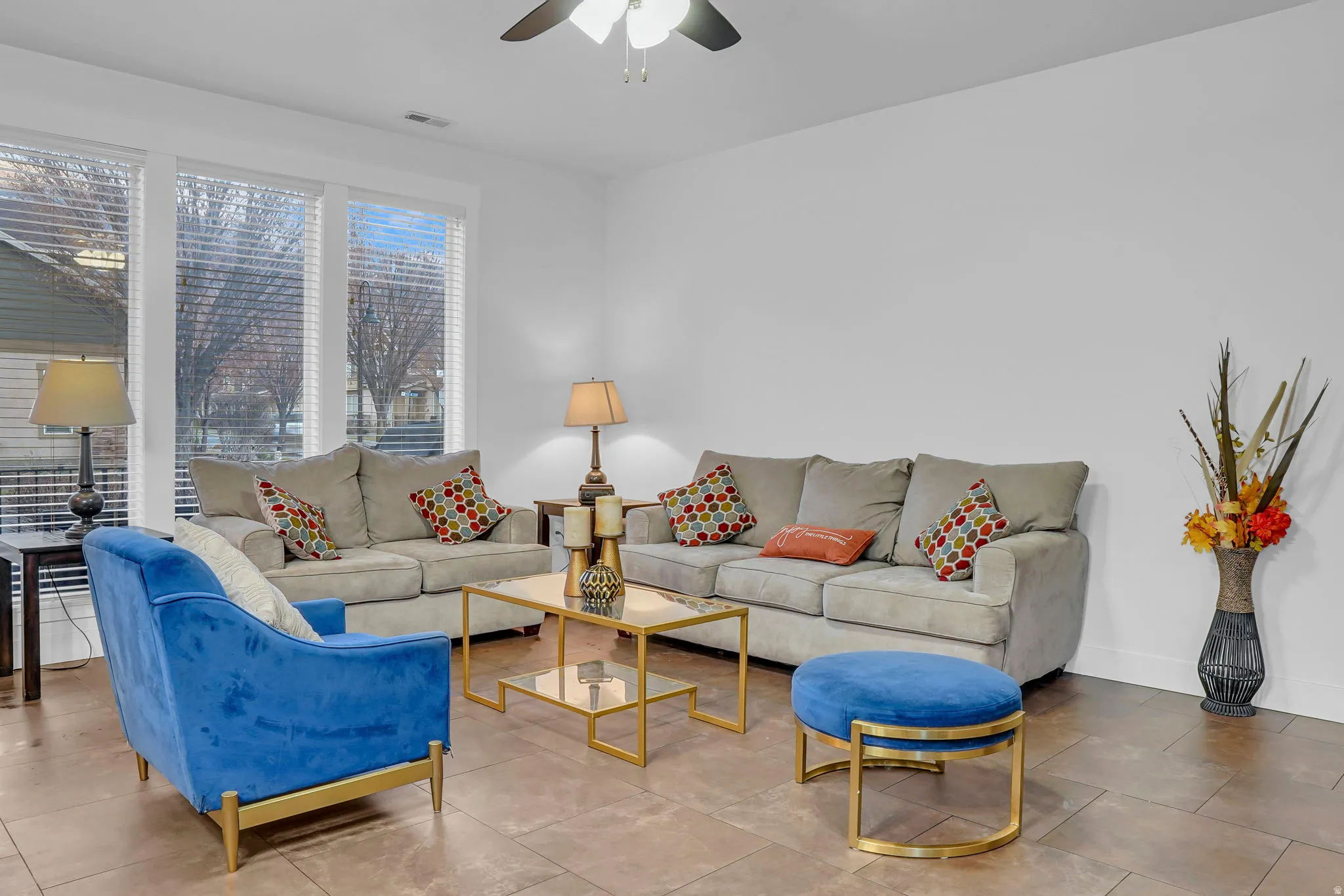 Tiled living room with a ceiling fan and baseboards
