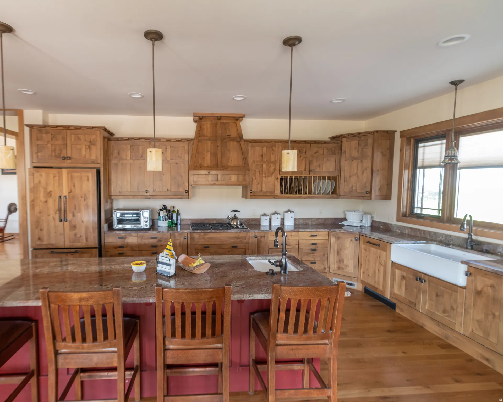 Kitchen featuring pendant lighting, paneled fridge, wood finish cabinets, dark wood finished floors, and dark stone countertops