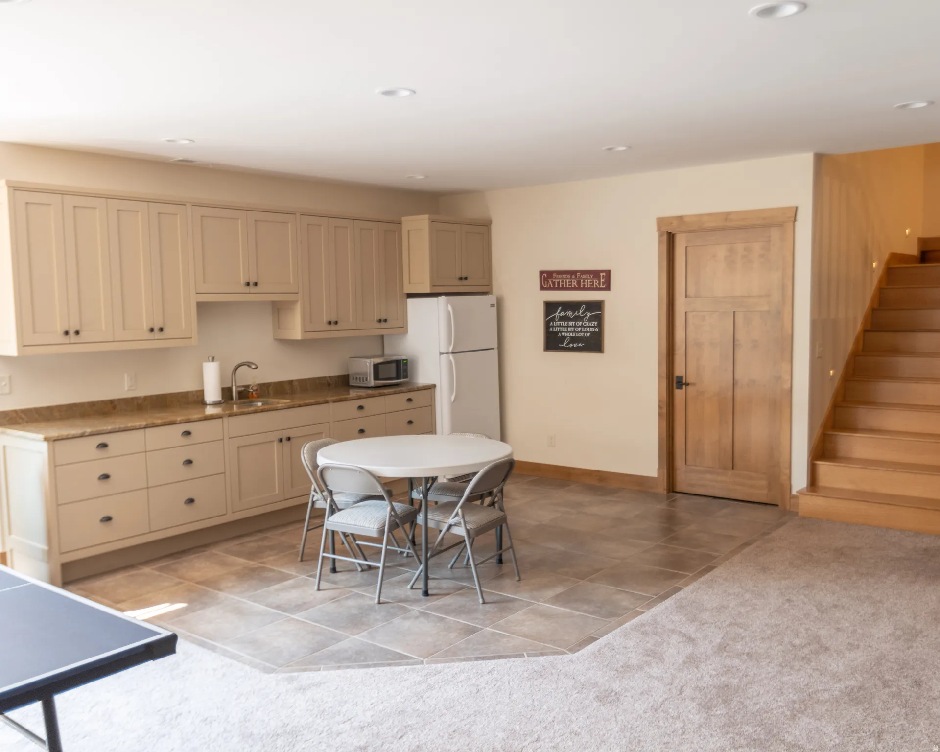 Kitchen with light tile patterned floors, light carpet, stainless steel microwave, recessed lighting, and freestanding refrigerator