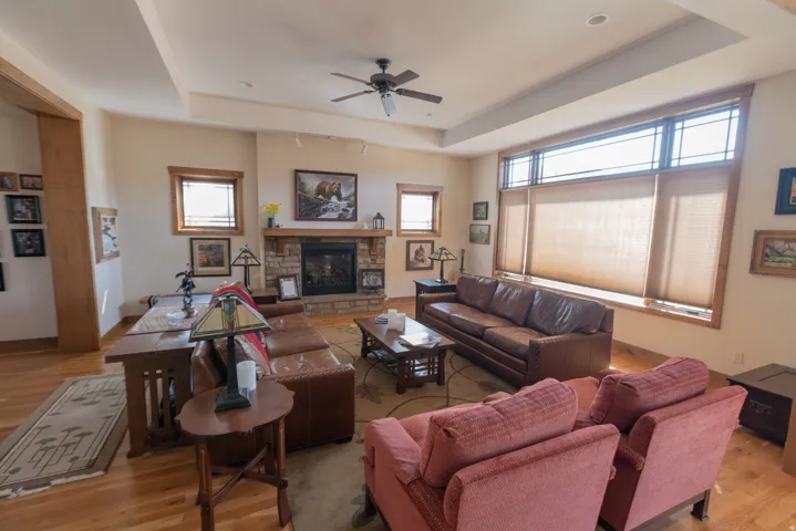 Living area featuring a tray ceiling, a ceiling fan, light wood-type flooring, and a fireplace