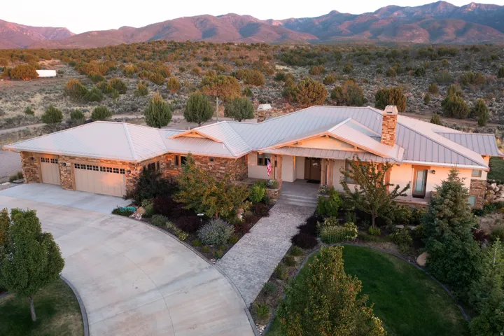 View of front of property featuring stone siding, a chimney, a mountain view, concrete driveway, and covered porch