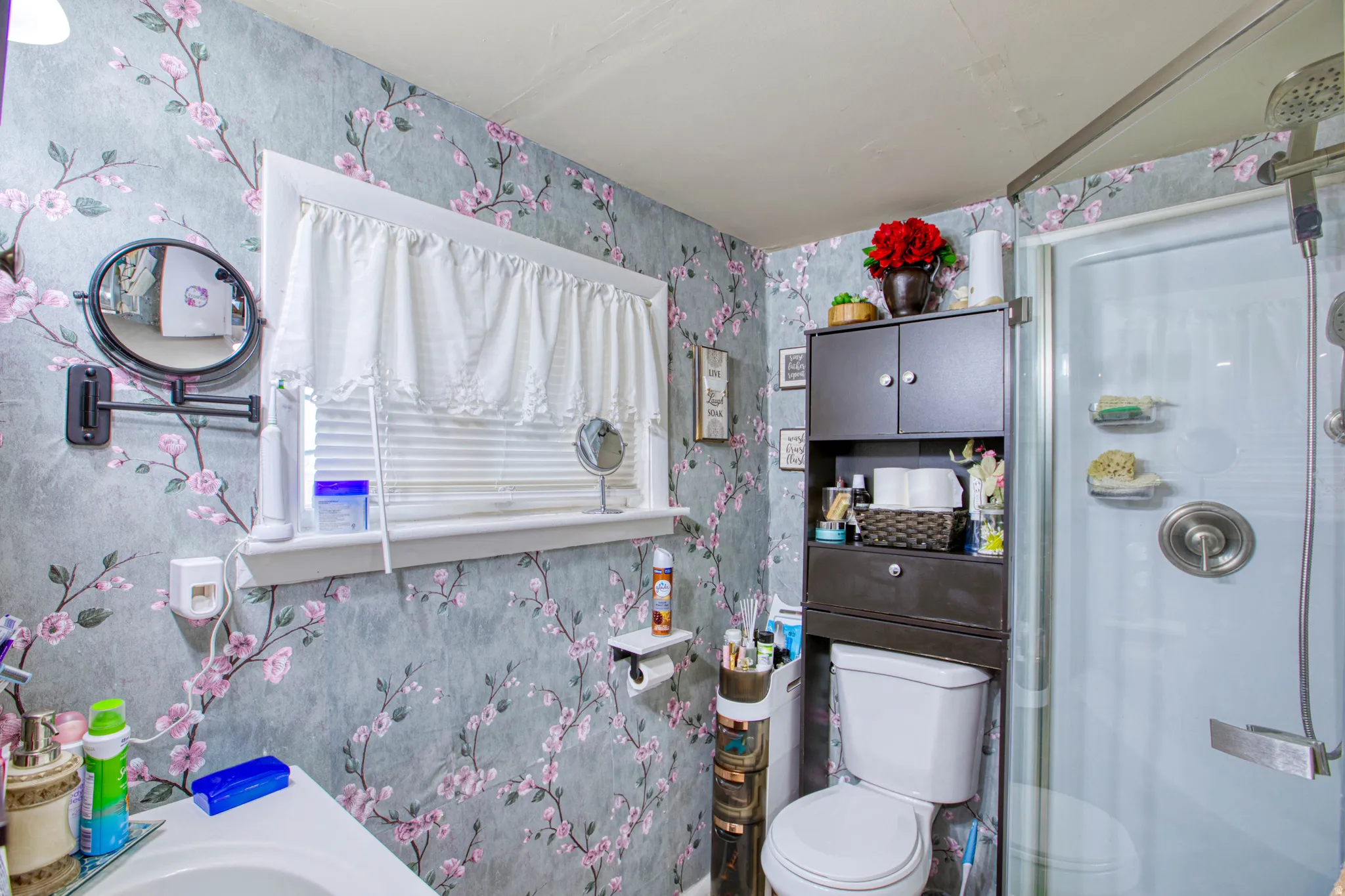 Bathroom featuring wallpapered walls, a shower with door, and vanity