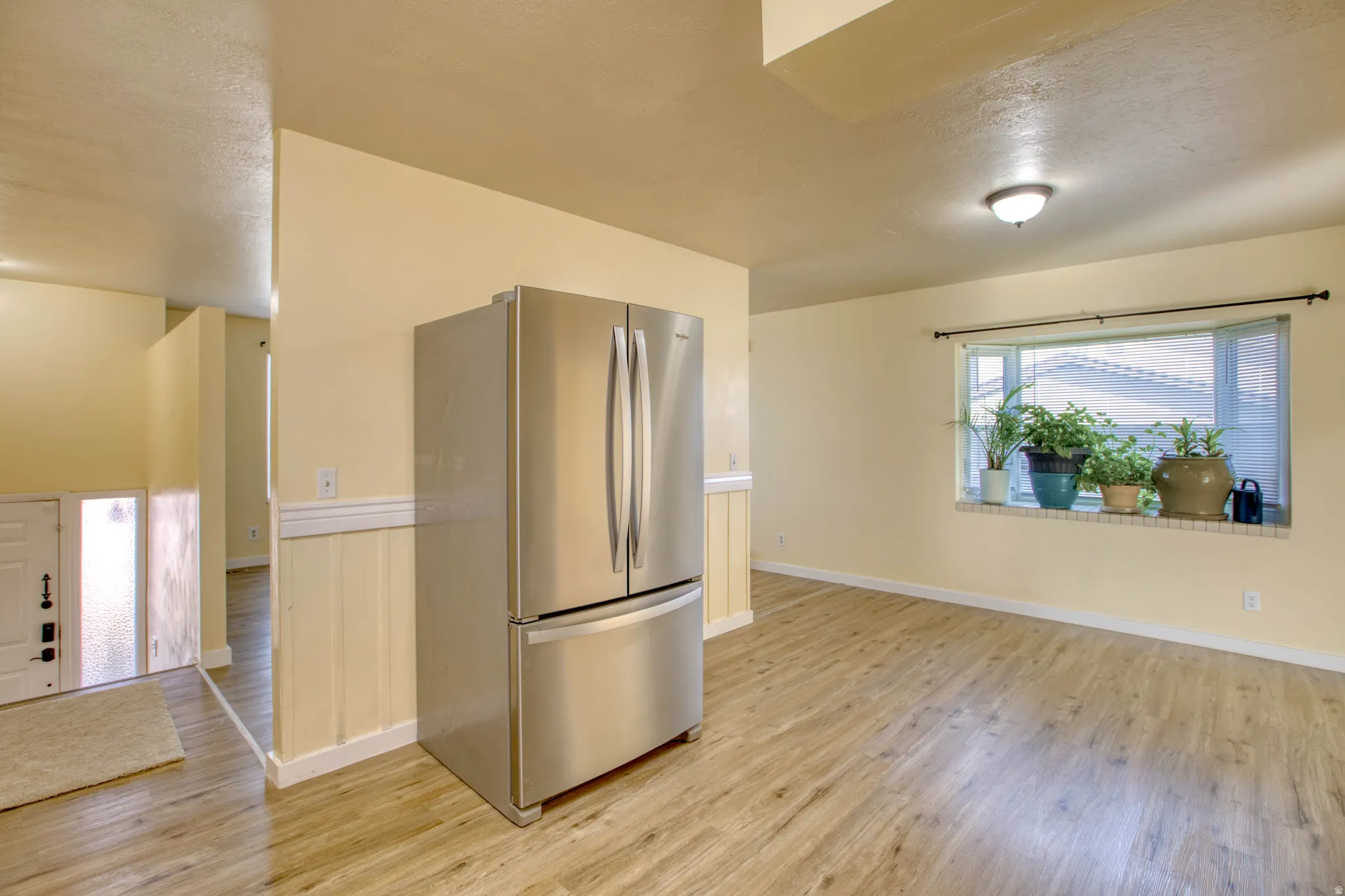 Kitchen with freestanding refrigerator, light wood finished floors, and a textured ceiling