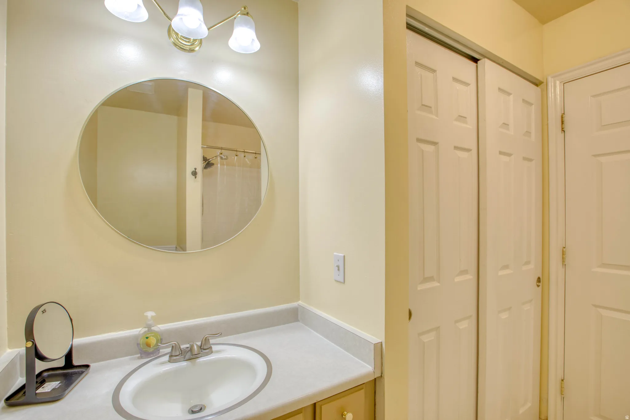 Bathroom with vanity, a shower with shower curtain, and a closet