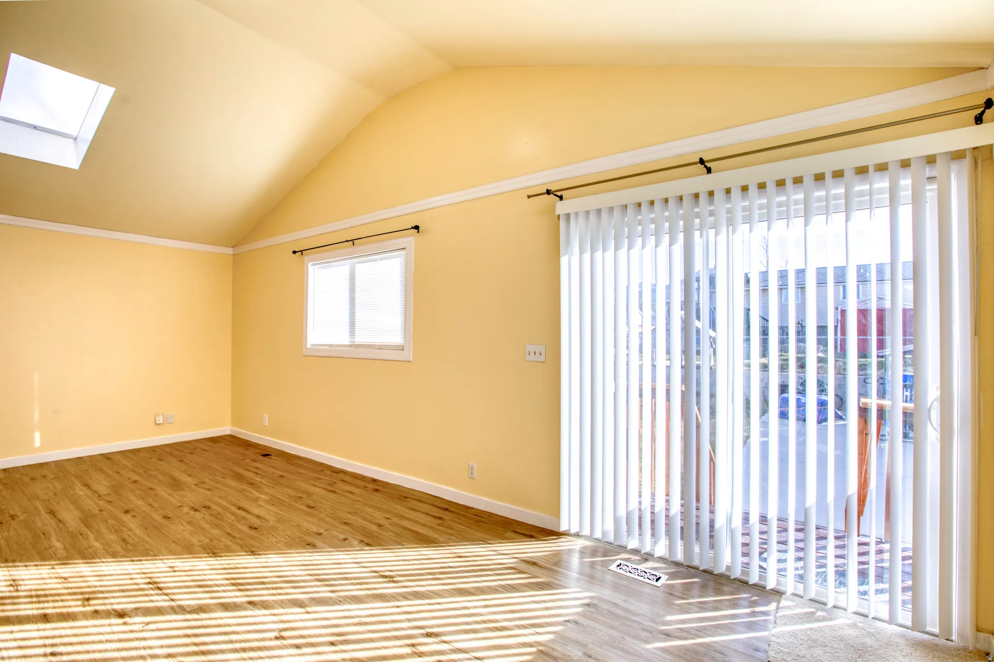 Empty room with lofted ceiling, a skylight, and wood finished floors