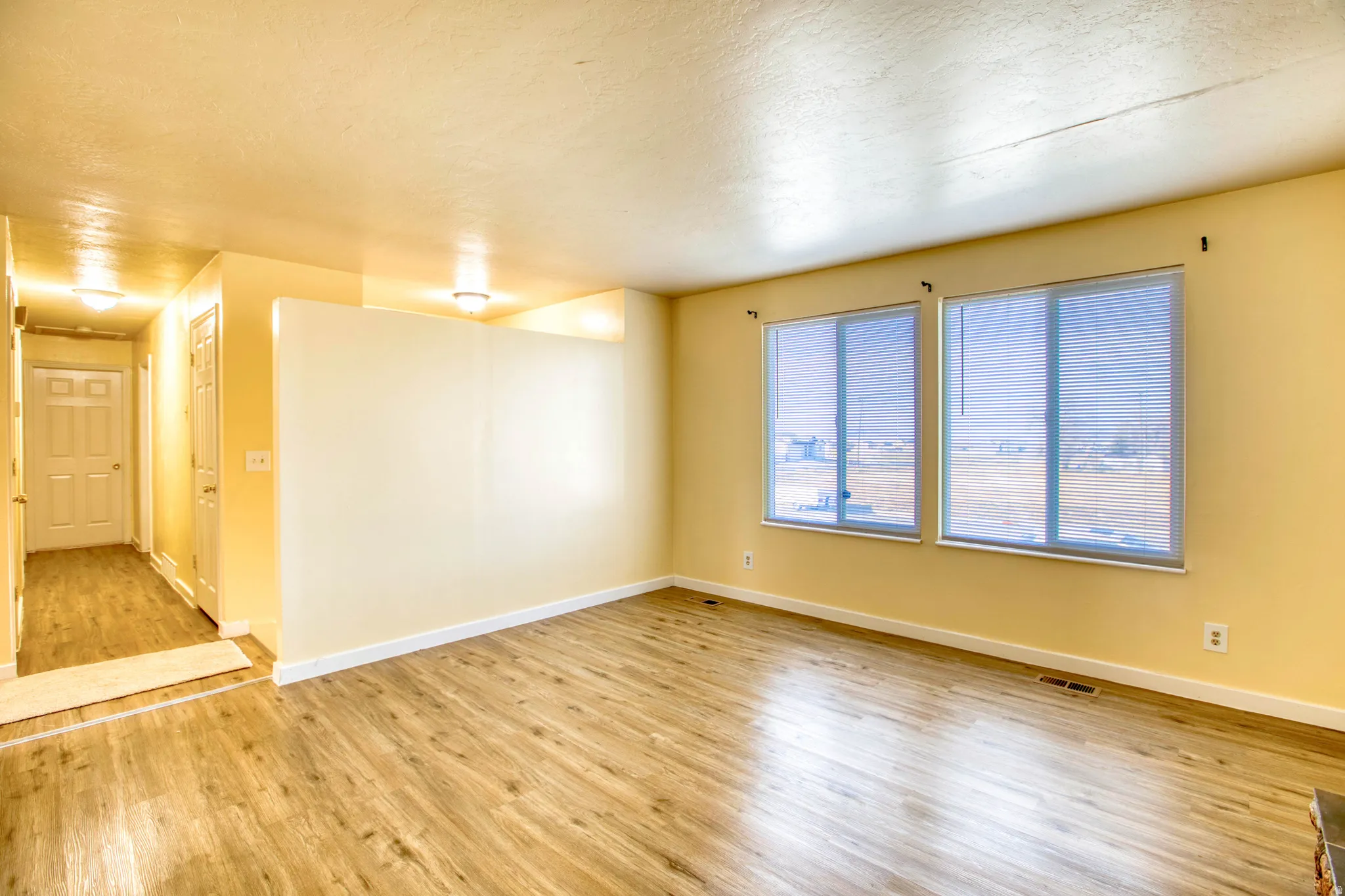 Empty room with light wood-type flooring and a textured ceiling