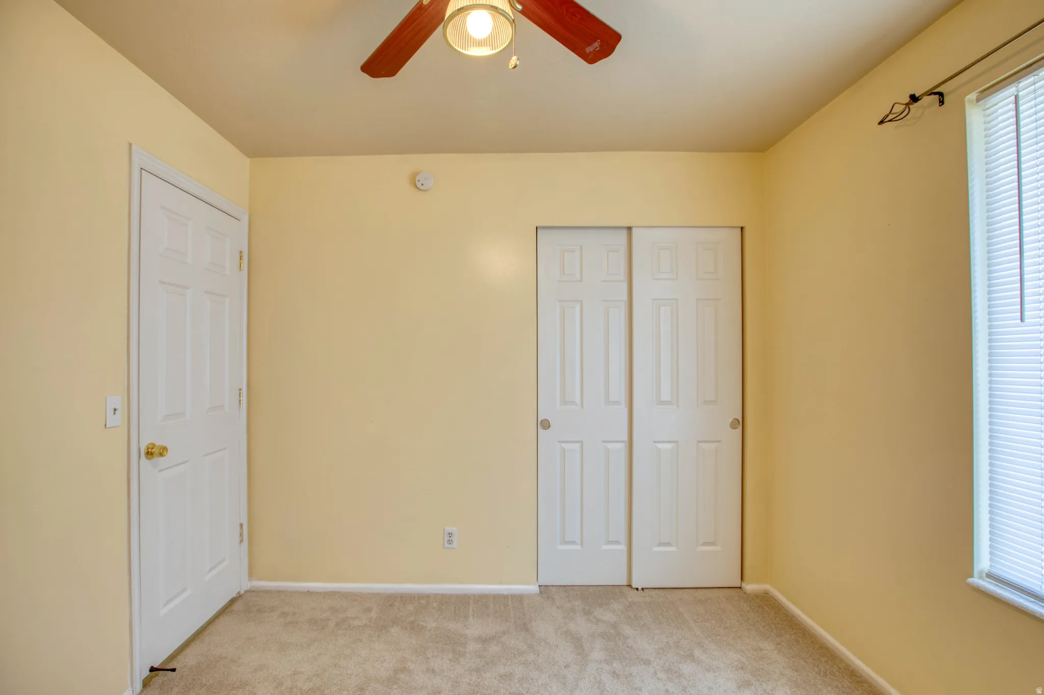 Unfurnished bedroom with light carpet, a closet, and a ceiling fan