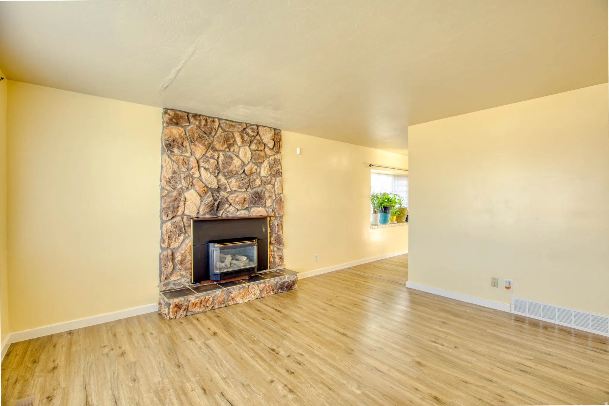 Unfurnished living room featuring a stone fireplace and light wood-style flooring