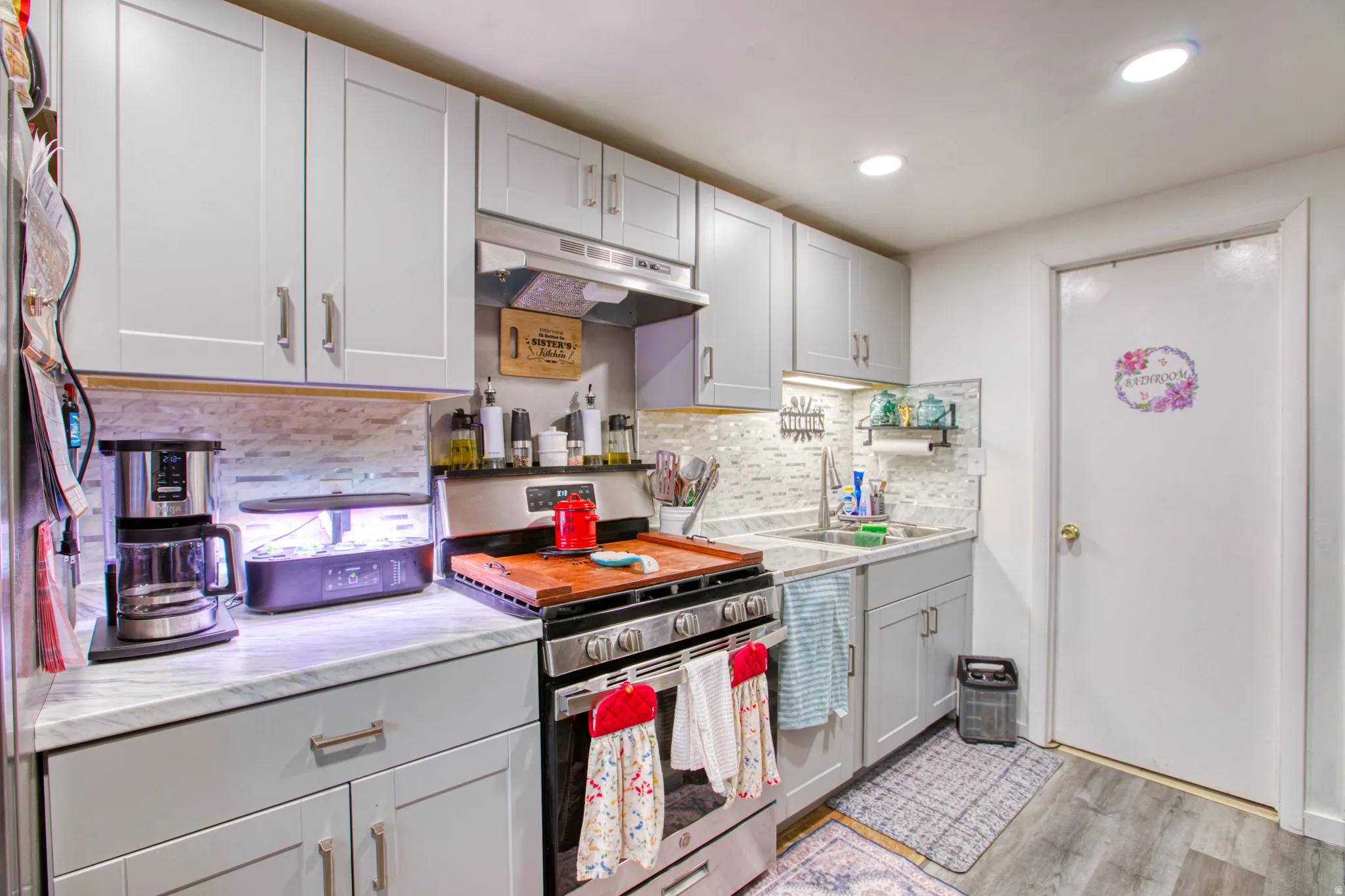 Kitchen with gas stove, light wood-type flooring, recessed lighting, light stone countertops, and backsplash