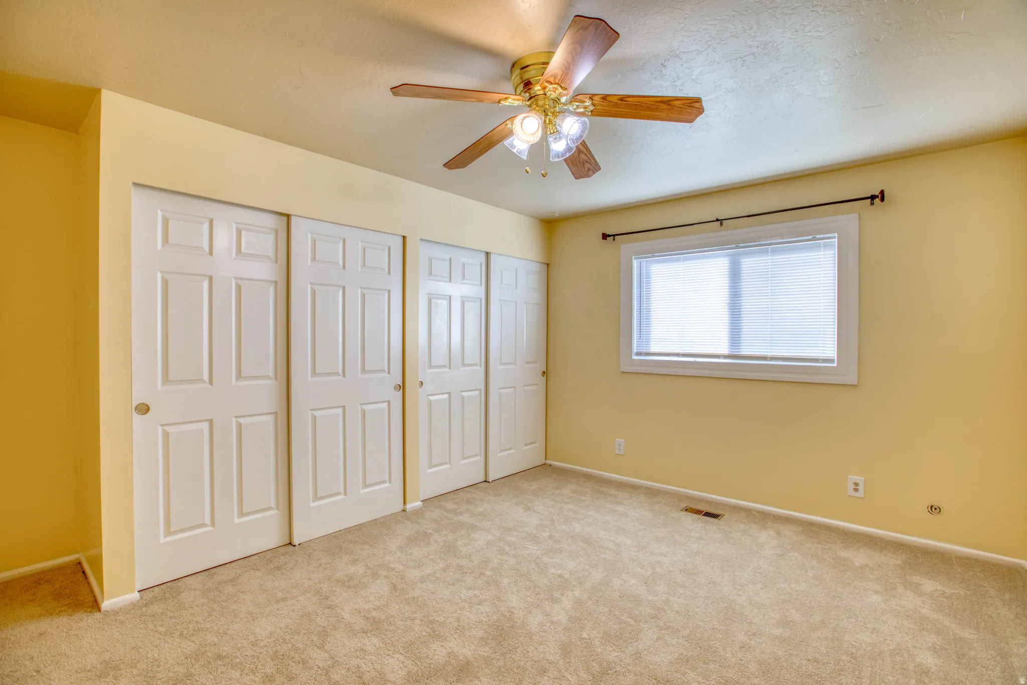Unfurnished bedroom with multiple closets, light carpet, and a ceiling fan
