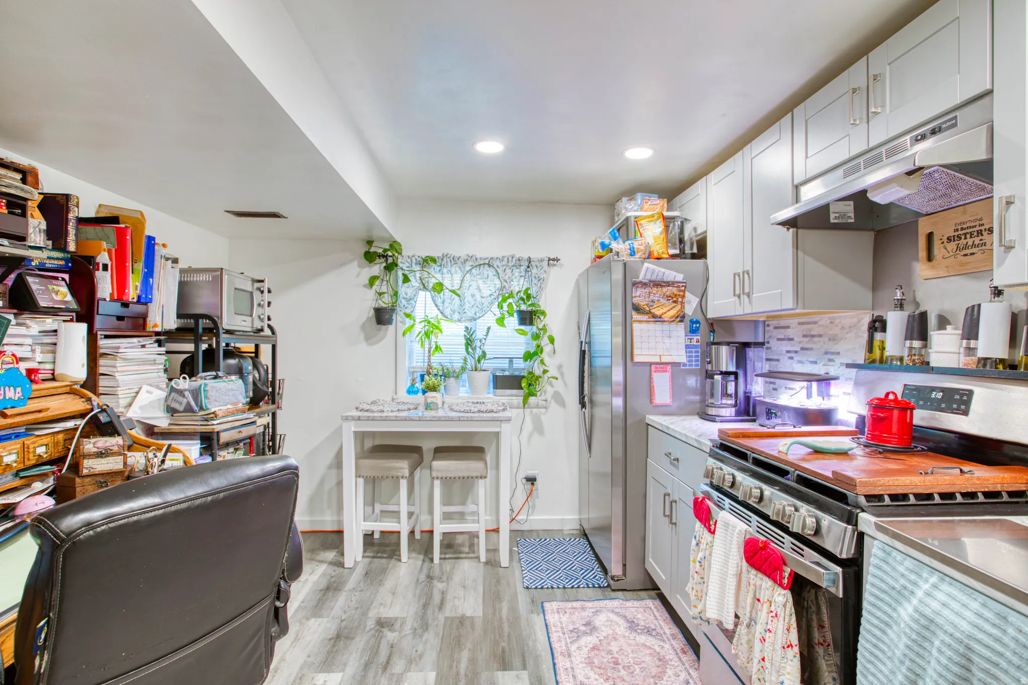 Kitchen featuring stainless steel appliances, light countertops, light wood-type flooring, tasteful backsplash, and gray cabinets