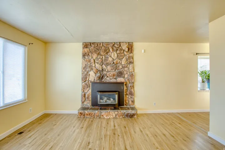 Unfurnished living room featuring a stone fireplace and wood finished floors