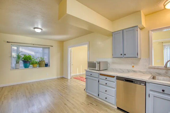 Kitchen featuring gray cabinetry, stainless steel appliances, decorative backsplash, light wood-type flooring, and a textured ceiling