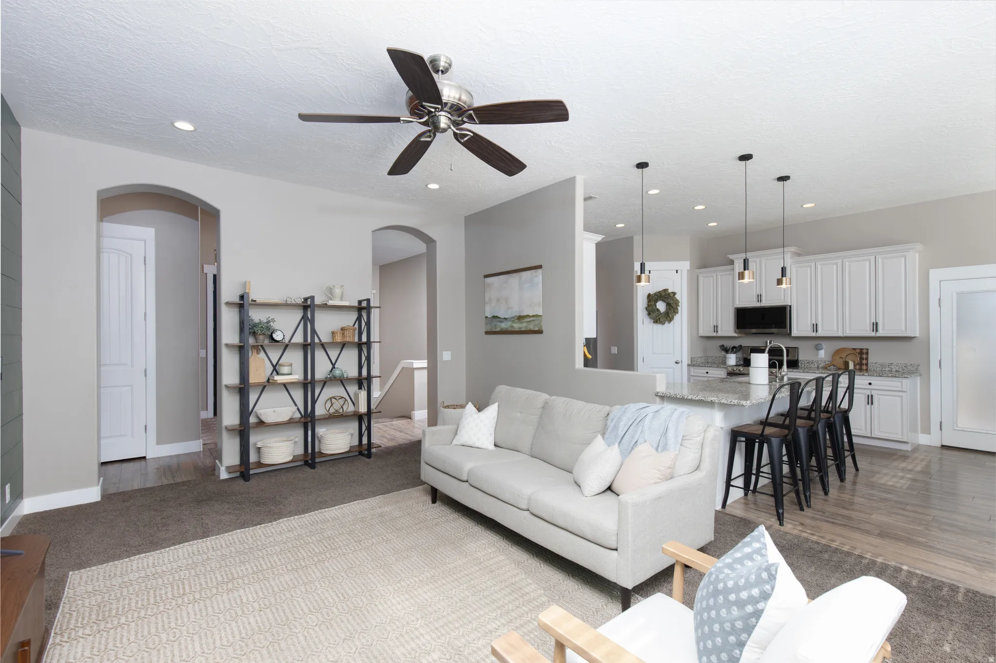 Living room featuring carpet, a ceiling fan, arched walkways, and recessed lighting