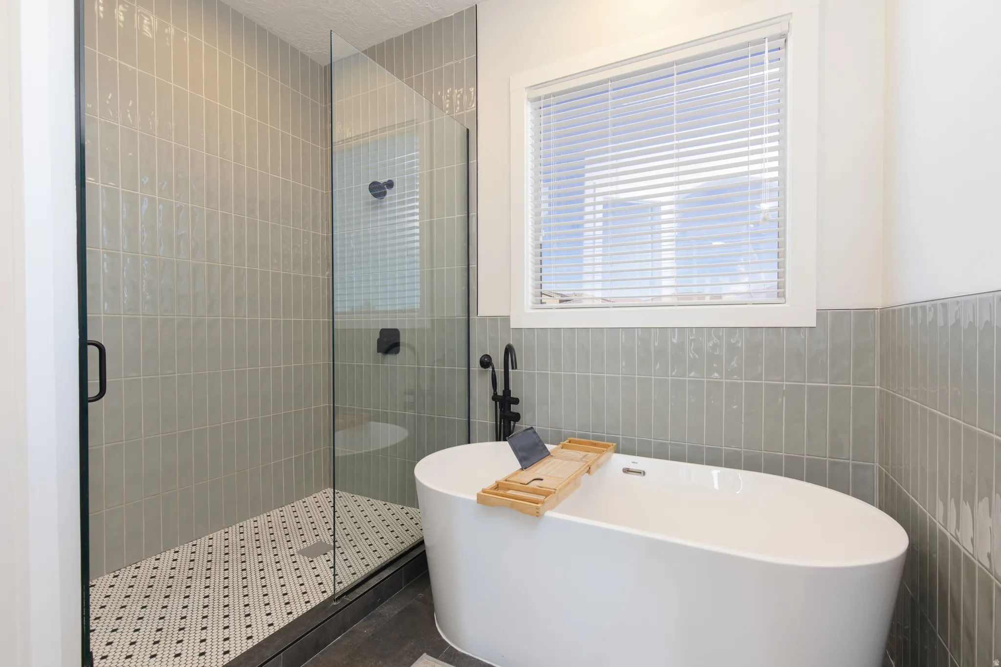 Full bathroom with a shower stall, a freestanding tub, and tile walls