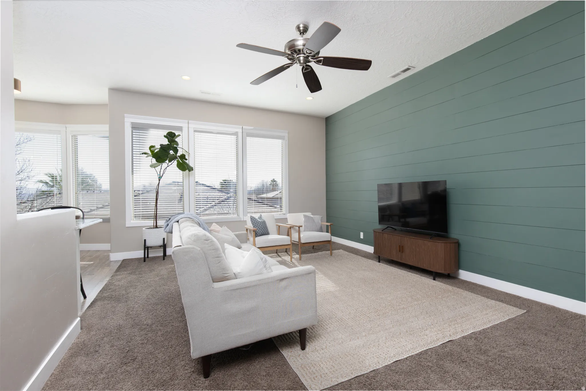 Carpeted living room featuring an accent wall, a ceiling fan, wood walls, and recessed lighting