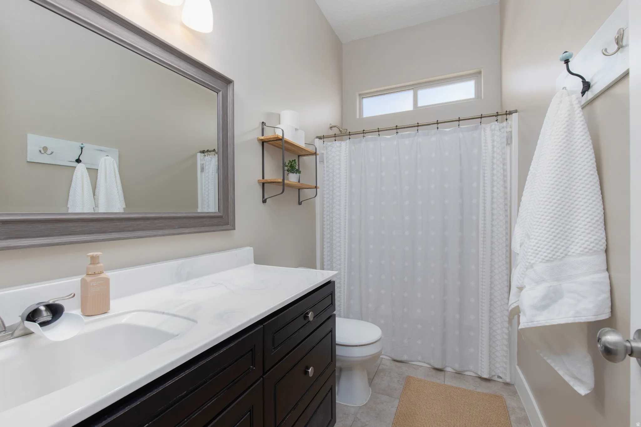 Bathroom with vanity, shower / tub combo, and light tile patterned floors