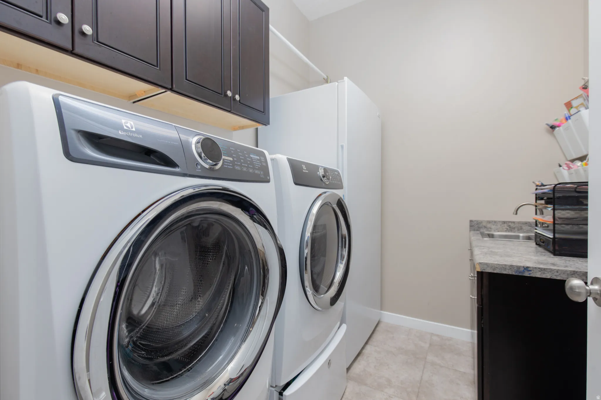 Laundry area featuring cabinet space, light tile patterned floors, and washing machine and dryer