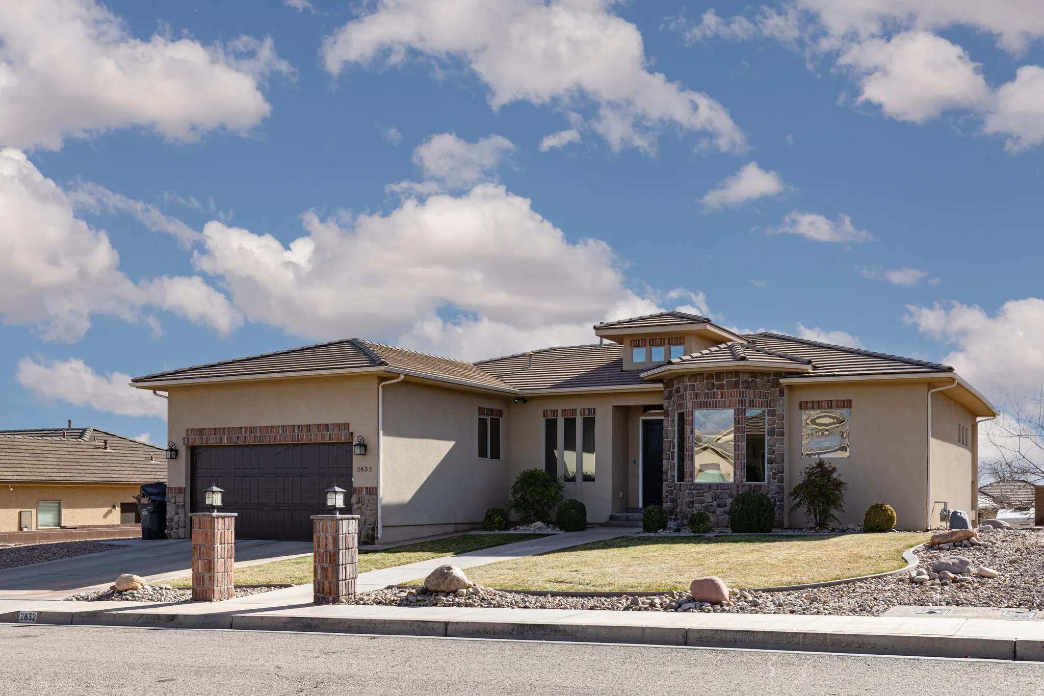 Prairie-style home with stucco siding, a front lawn, a garage, and driveway