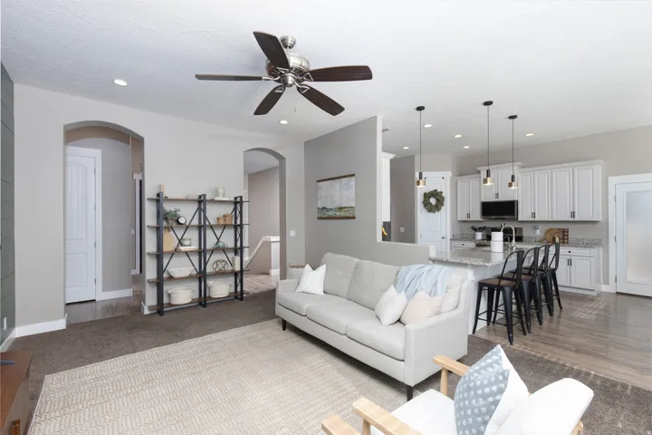Living room featuring carpet, a ceiling fan, arched walkways, and recessed lighting