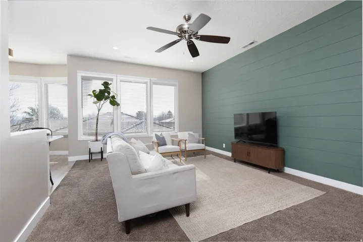 Carpeted living room featuring an accent wall, a ceiling fan, wood walls, and recessed lighting