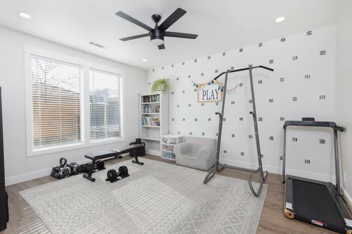 Workout area with light wood-type flooring, a ceiling fan, and recessed lighting