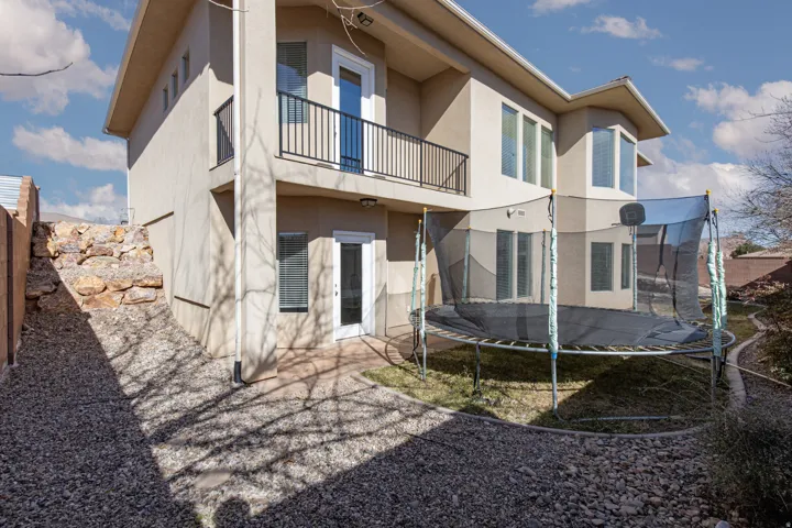 Back of house with a balcony, stucco siding, a patio area, and a trampoline