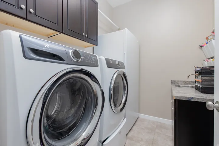 Laundry area featuring cabinet space, light tile patterned floors, and washing machine and dryer