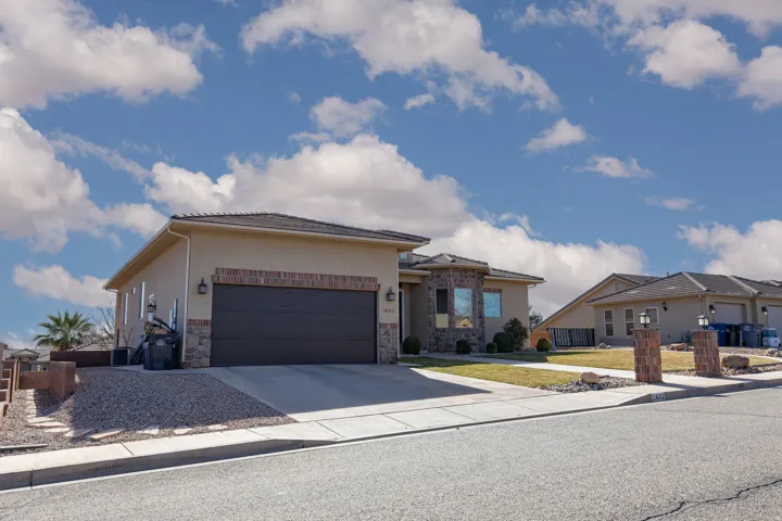 Prairie-style home with driveway, stucco siding, a garage, stone siding, and a front yard