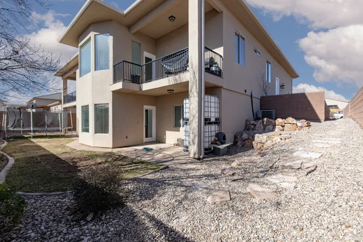 Back of house with a balcony, a trampoline, stucco siding, and a patio area