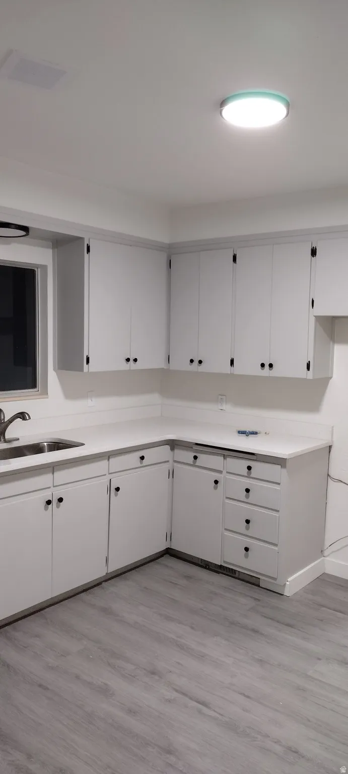 Kitchen featuring light wood-type flooring, white granite countertops, and white cabinetry