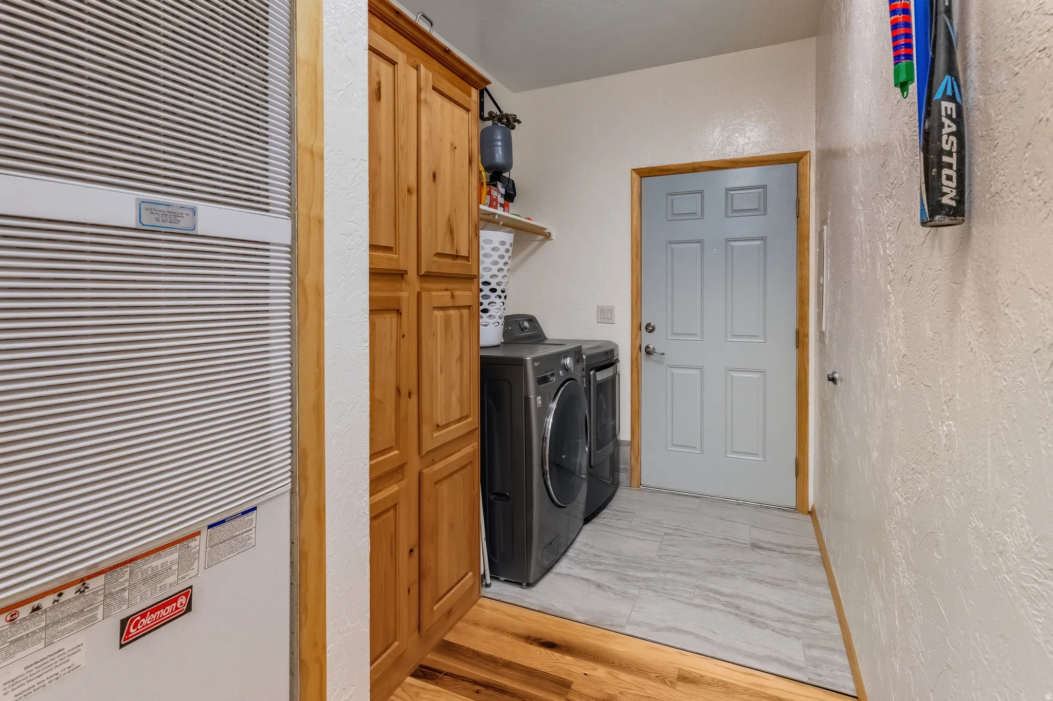 Laundry room featuring a heating unit, washer and clothes dryer, and light wood-style flooring