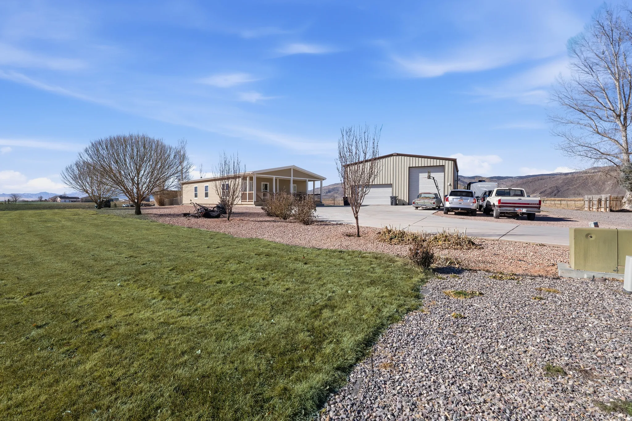 Rear view of property featuring a detached garage, an outdoor structure, a mountain view, and a yard